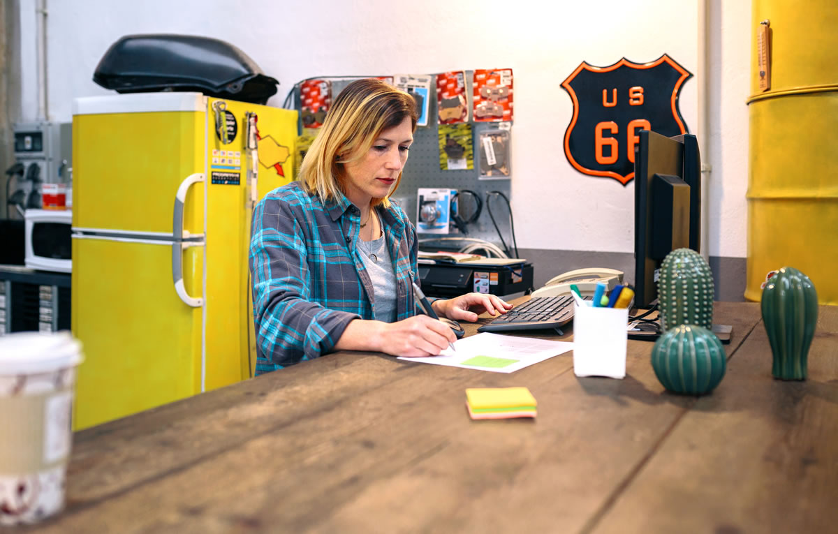 A small-business owner working on a laptop at her shop counter